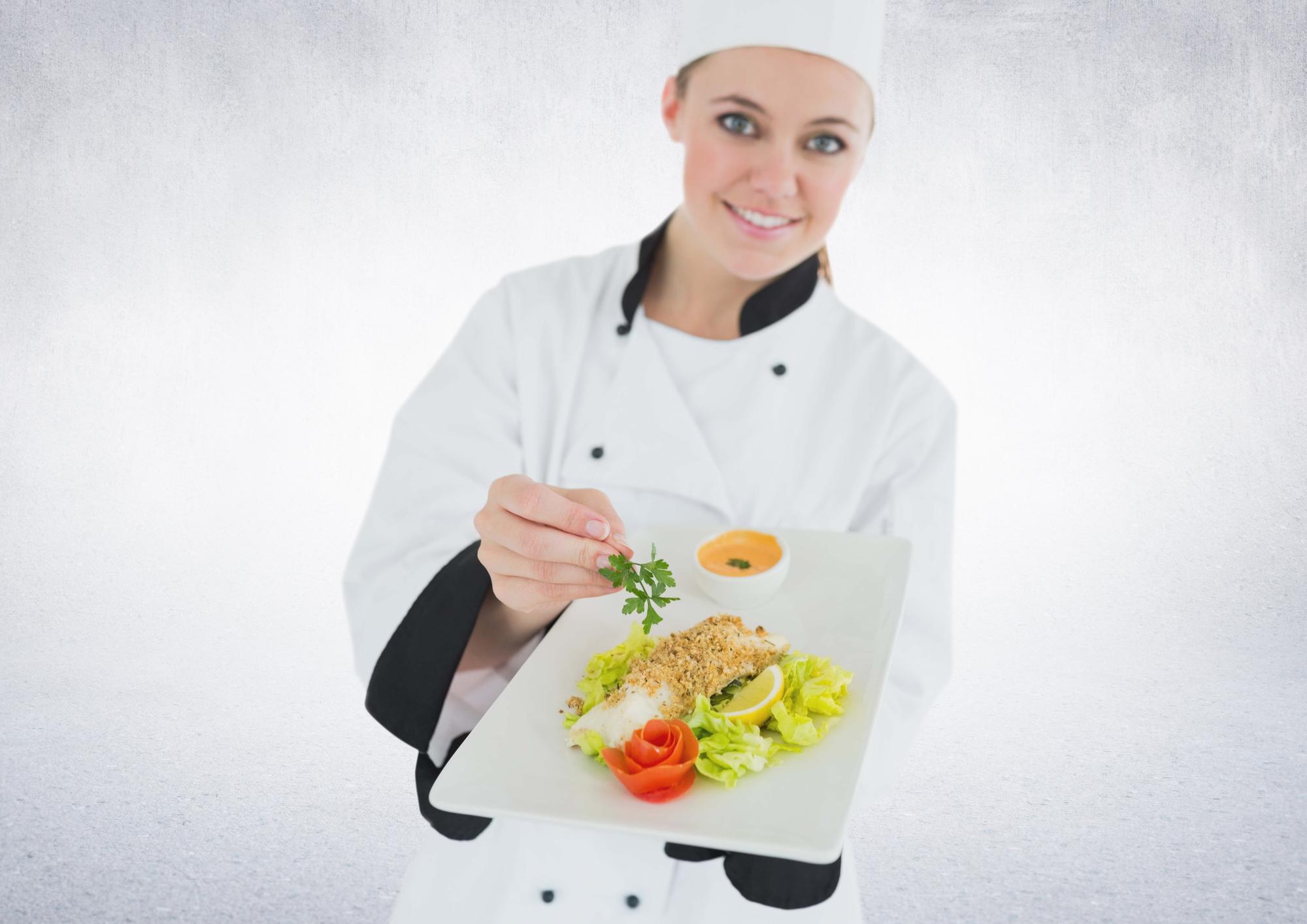 Chef smiling holding a plated dish